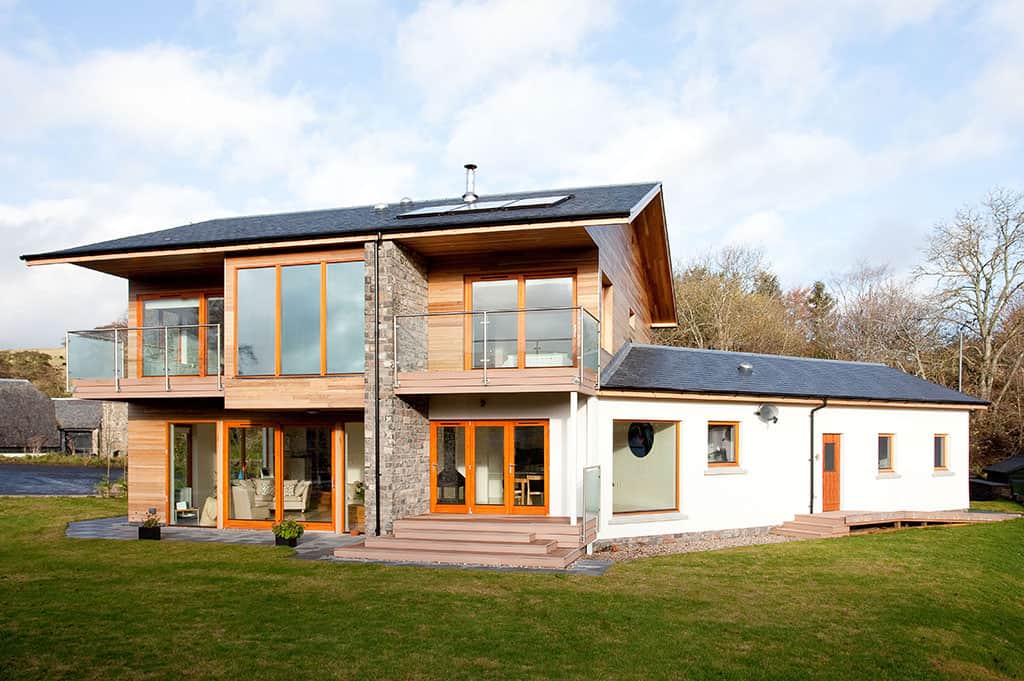 Self-build home exterior finished in stone, timber and render