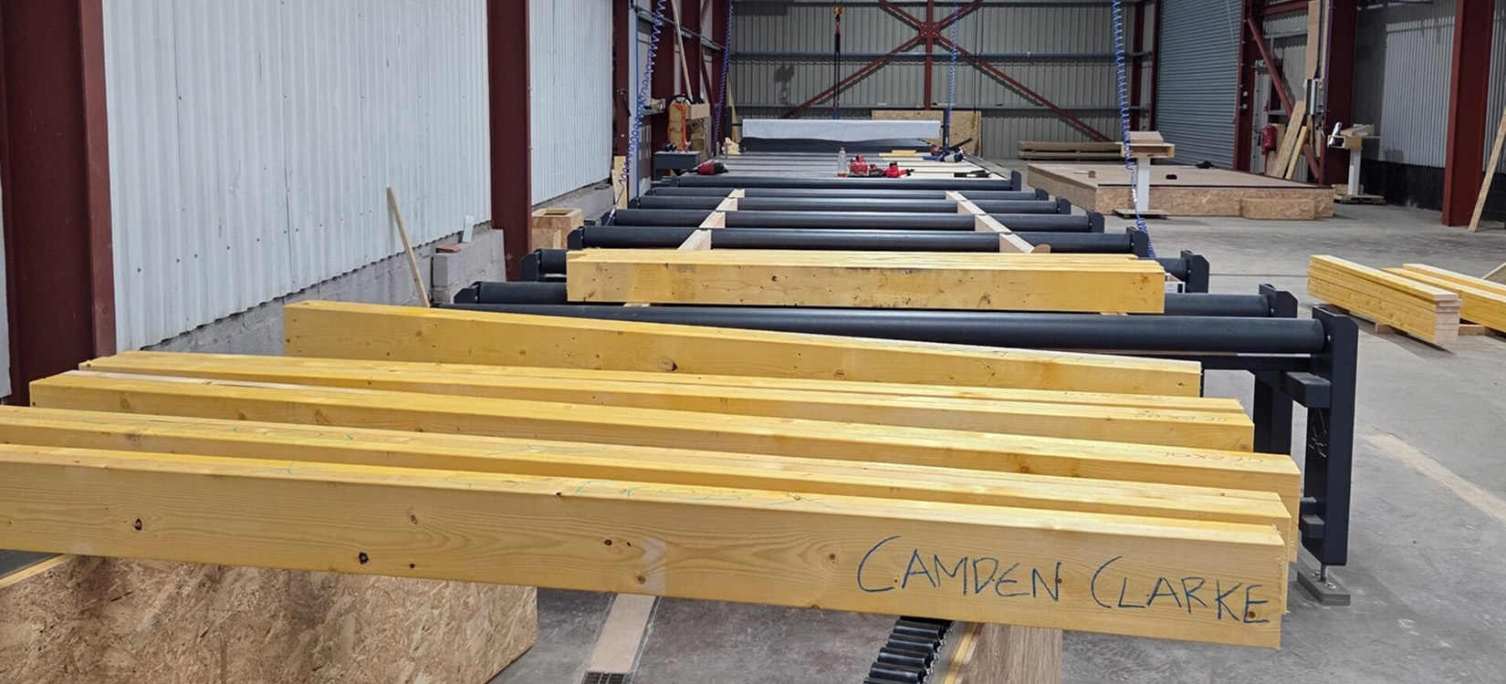 Timber frame components laid out in the Fleming Homes workshop before delivery