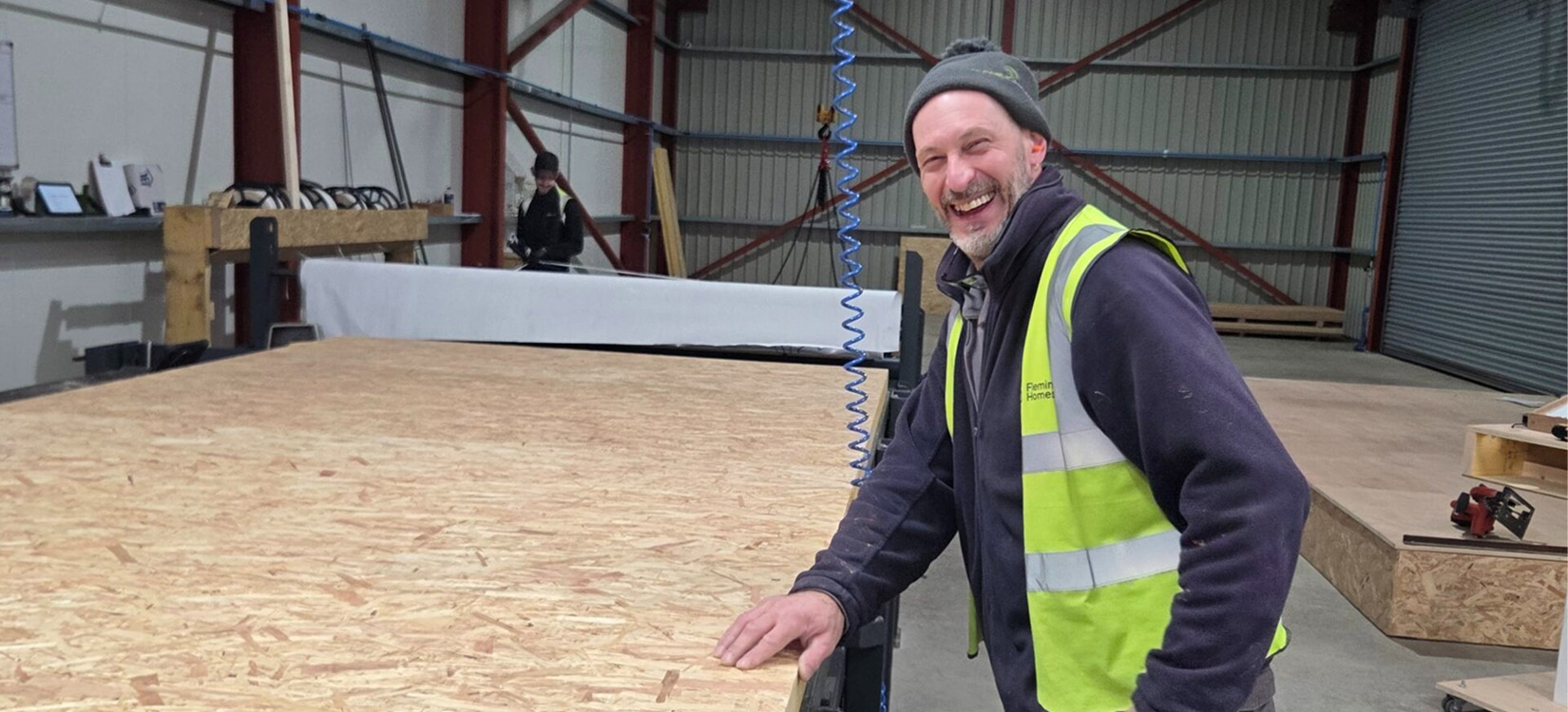 Fleming Homes team member beside a timber frame floor panel in the workshop