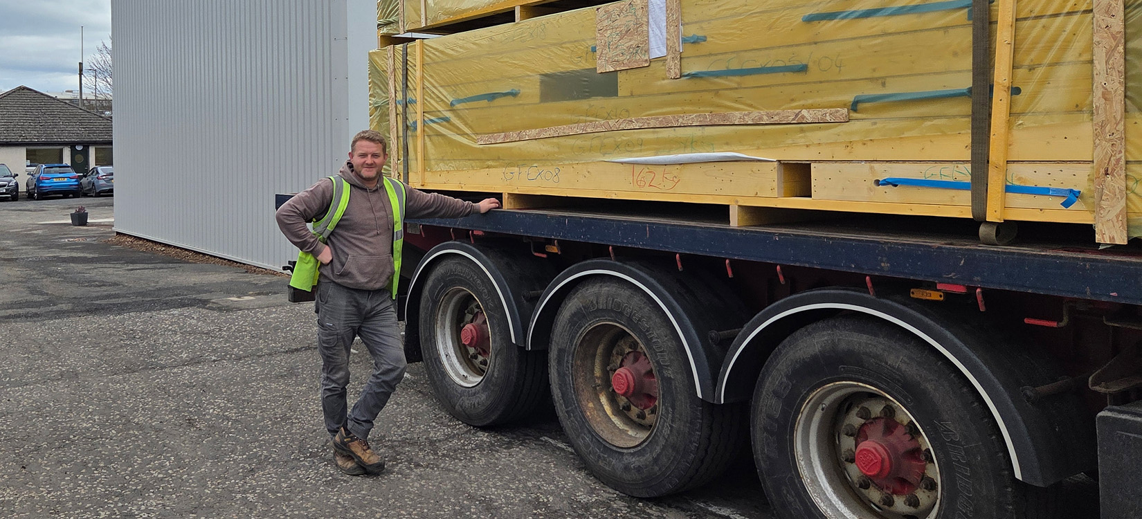 Timber frame sections being transported for a single-storey stone and timber home project in Turriff, UK