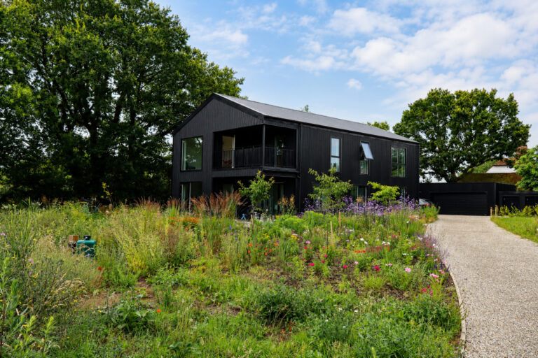 Aerial view of a completed black barn-style timber frame self-build home in the Kent countryside.